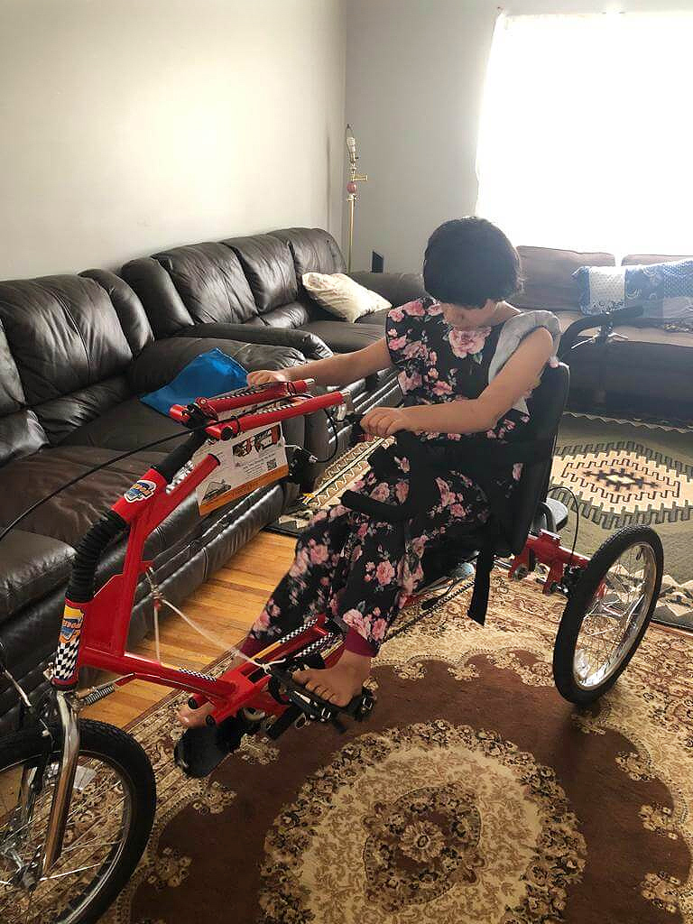 Farah with her new adapted bicycle in her home